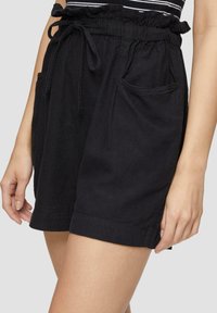Shorts en coton noir avec une taille élastique, cordon de serrage réglable et deux poches avant. Texture lisse et design simple.