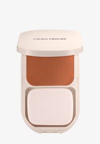 Estuche compacto beige etiquetado como Laura Mercier que contiene polvo de maquillaje naranja quemado y una esponja aplicadora blanca rectangular.