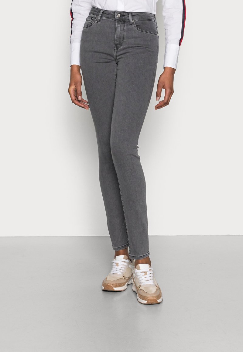 Gray skinny jeans with a classic fit, featuring a high waist, front pockets, and subtle stitching details. Paired with beige sneakers.