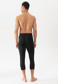 Schwarze Sportleggings mit figurbetontem Design, nahtlosem Bund, drei Viertellängen und strukturierten Panelakzenten.