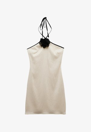Beige halterjurk met zwarte bies en een zwarte stoffen bloemdetaillering bij de hals, gemaakt van een licht glanzende, gestructureerde stof.