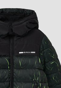 Giacca a vento nera con cappuccio, caratterizzata da un motivo testurizzato verde e nero, hardware argento e una tasca con zip sul davanti.