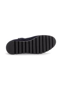 Semelle en caoutchouc noir d'une chaussure avec de profonds rainures horizontales et le logo "Gabor", vue du dessous sur fond blanc.