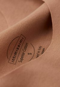 Bavlněná látka v jemné béžové barvě, s etiketou s názvem "Intimissimi", velikost "S" a nápisem "Superior Cotton" tištěným černou barvou.