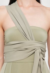 Rochie verde salvie cu un design fără bretele, din material ușor, cu țesătură drapată și răsucită și un detaliu legat în talie.