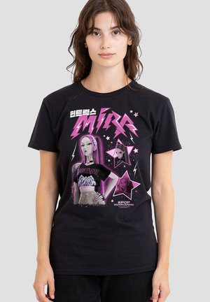 Black cotton t-shirt featuring a graphic design with pink colors, star accents, and K-pop themed imagery, including the text “MIRA” and “KPOP DEMON HUNTRESS.”