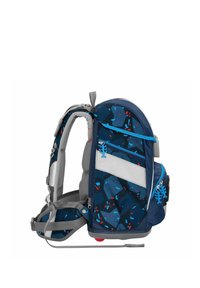 Sac à dos bleu et gris avec un motif géométrique, doté de fermetures éclair avec des tirettes décoratives, et d'un grand panneau blanc pour un étiquetage personnalisé.