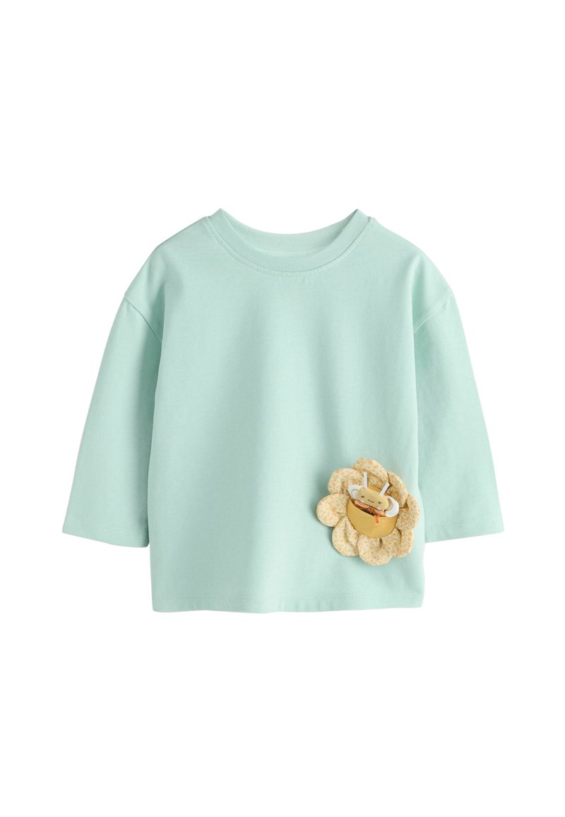 Camiseta de algodón azul claro con cuello redondo y mangas tres cuartos, con un diseño de flor 3D y un pequeño detalle de abeja.