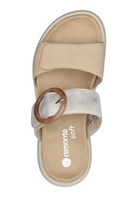 Sandale à glissière beige et taupe avec une texture en suédine douce, dotée d'un accent en bois circulaire et d'une semelle intérieure rembourrée. Nom de la marque imprimé à l'intérieur.