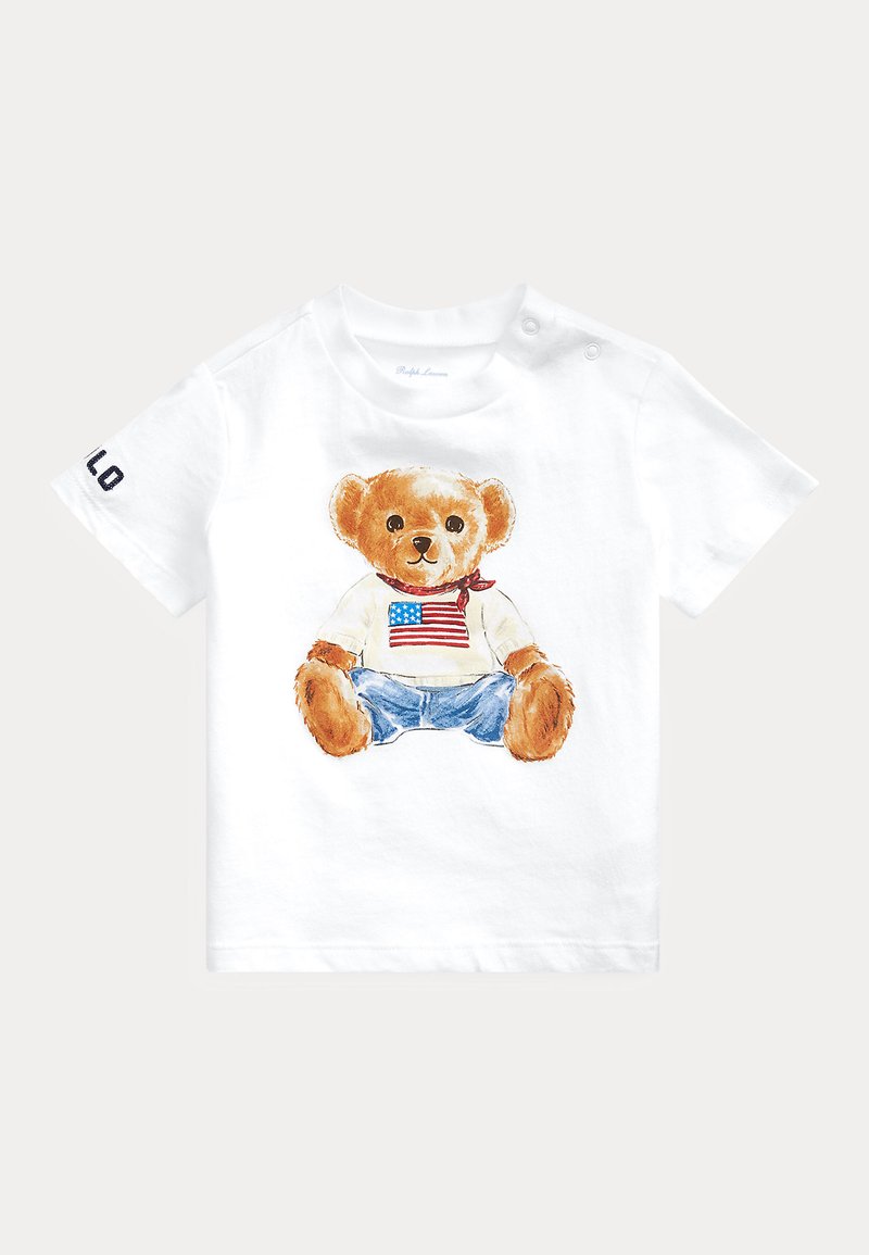 Camiseta blanca para niño pequeño con un osito de peluche que lleva bufanda, vaqueros y una camisa con la bandera americana, y la palabra "POLO" en la manga.