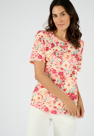Korte mouwen bloemen top met een lichte perzikkleurige achtergrond en roze, rode en groene patronen. Zachte stof met een ronde halslijn en een relaxte pasvorm.