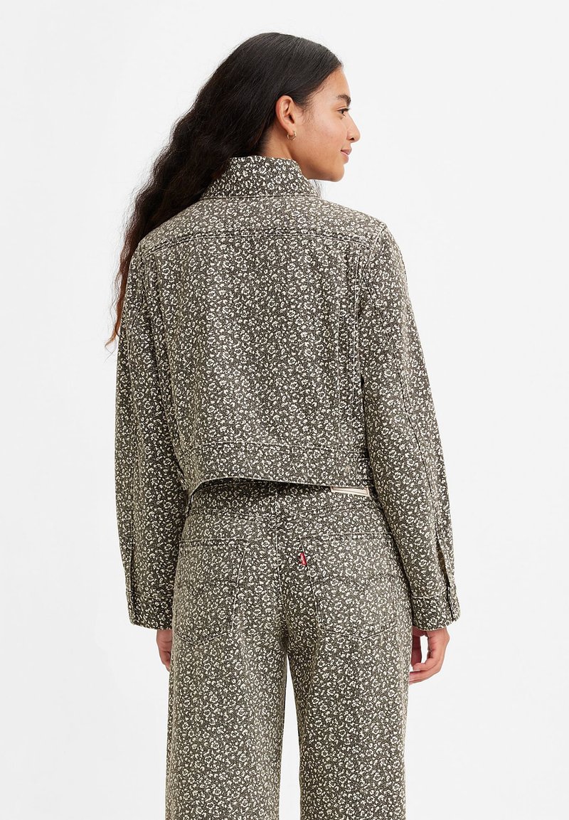 Chaqueta corta con cuello alto, hecha de un tejido texturizado que presenta un pequeño estampado floral en tonos apagados de verde y blanco roto.