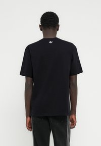 Μαύρο βαμβακερό κοντομάνικο μπλουζάκι με μικρό λευκό λογότυπο στο πίσω μέρος του λαιμού. Στρογγυλή λαιμόκοψη και άνετη εφαρμογή.