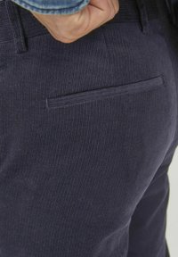 Mornarsko plave pantalone od kordura s rebrastom teksturom, s stražnjim džepom bez šavova, strukturiranim pojasom i suptilnim detaljima šivanja.