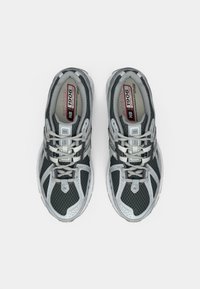 Gray athletic shoes with mesh upper, reflective accents, and rubber soles. Features laces and a padded collar for support. Model: New Balance 1906.