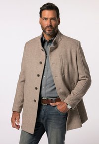 Abrigo de mezcla de lana marrón claro con un cuello alto, cinco botones y bolsillos laterales, combinado con una camisa azul y jeans de mezclilla.