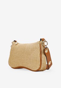 Bolso de paja trenzada con forma curva, color beige, detalles en cuero marrón y herrajes en tono dorado. Cuenta con una correa ajustable y cierre de cremallera.