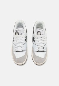 White and gray sneakers featuring a mix of leather and suede, with a lace-up design, rounded toe, and black accents on the sides.