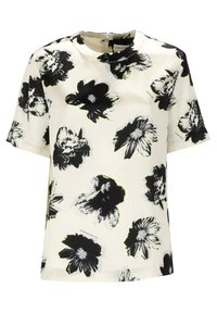 Blouse blanche à manches courtes avec un motif floral noir et gris, décolleté rond et fermeture éclair visible au dos.