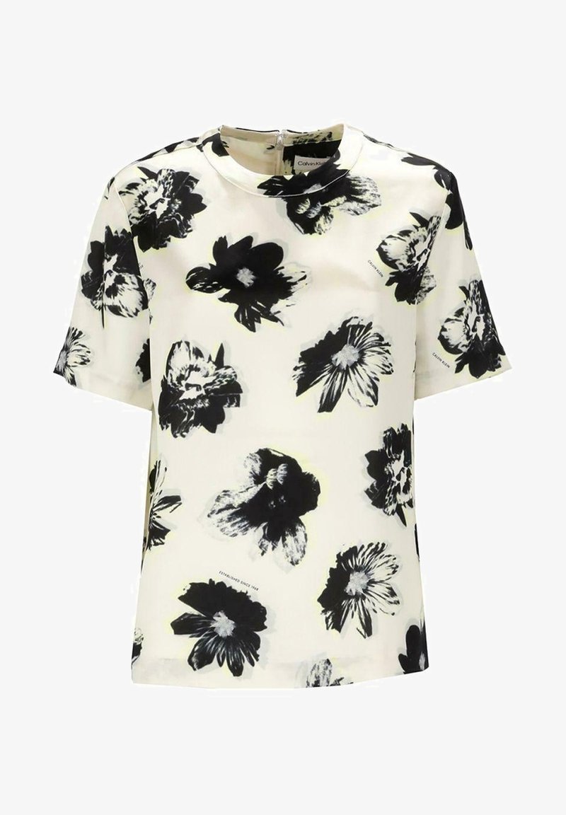 Kortærmet hvid bluse med sort og grå blomsterdesign, rund halsudskæring og synlig lynlås på ryggen.