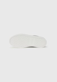 Witte sneakerzool met een getextureerd grippatroon, voorzien van een vlak profiel en een subtiele merklogo in het midden. Glad afgewerkte randen en duurzaam materiaal.