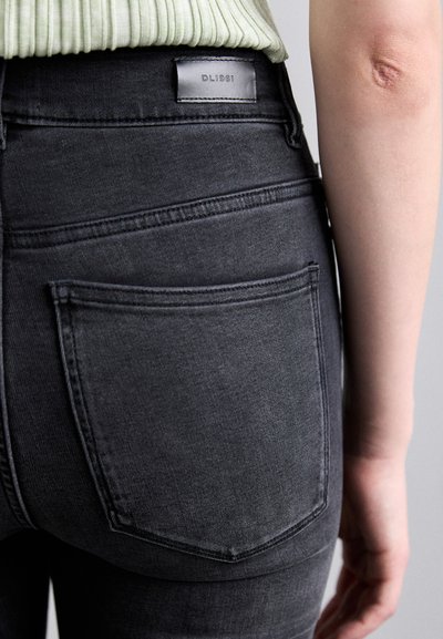 High-waisted black jeans with a smooth texture, featuring back pockets and a leather label on the waistband labeled "DL1961."