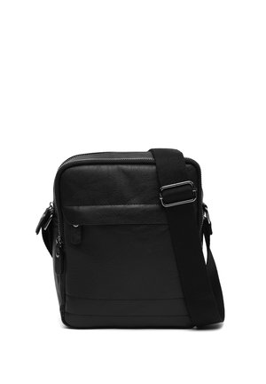 Petit sac bandoulière en cuir noir avec poche zippée à l'avant et sangle en tissu réglable sur fond blanc.
