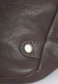 Accessorio in pelle marrone con superficie testurizzata, logo impresso e un bottone a scatto decorativo con dettagli di cucitura.