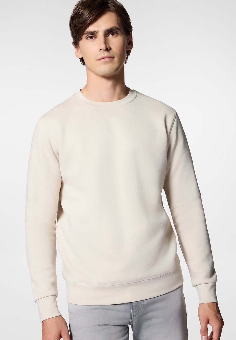 Kremowy sweter z długim rękawem, ściągaczami na mankietach i okrągłym dekoltem. Miękka tekstura o luźnym kroju, z minimalnymi detalami szwów.