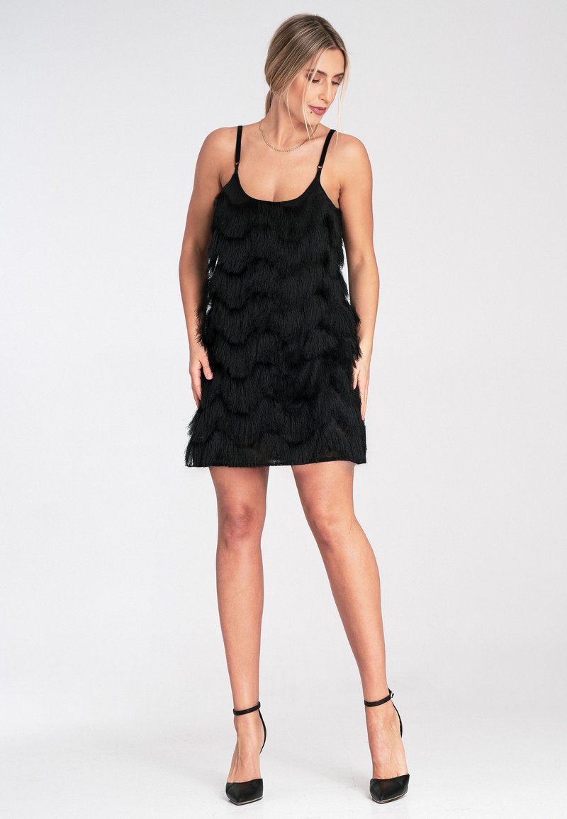 Schwarzes Kleid mit geschichteten Fransen, dünnen Trägern und einem knielangen Schnitt. Die Textur ist weich und weist ein wellenartiges Muster auf.