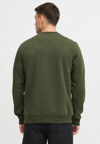 Olivenfarget genser med lange ermer, rund hals, ribbede mansjetter og en lett teksturert overflate. Bakviewet viser en glatt, tettsittende silhuett.