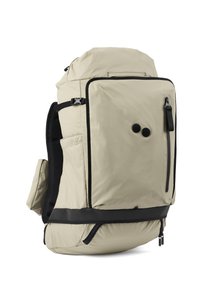 Beige Nylon-Rucksack mit einem oberen Klappdeckel, mehreren Außentaschen, Netzträgern und schwarzen Reißverschlussakzenten. Verfügt über einen gepolsterten Boden und Knöpfe.