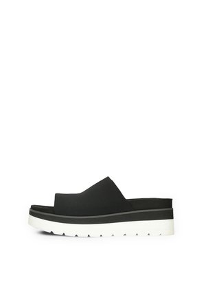 Chanclas negras con una parte superior texturizada, tiras anchas y una suela de goma blanca gruesa con un fondo con patrón de olas.