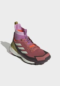 Lilla og maroon atletisk sko med en sok-lignende overdel, tre hvide striber, tekstureret overflade og flerfarvede accenter på kragen.