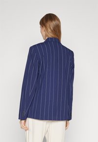 Námořnický modrý sako s jemným pruhováním, se zapínáním na jeden rozvent, s klopami a manžetami na tři knoflíky, ušité z pevných materiálů.