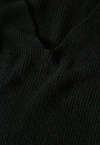 Gros plan sur un tissu en maille côtelée noire avec une texture douce et un motif côtelé vertical visible.