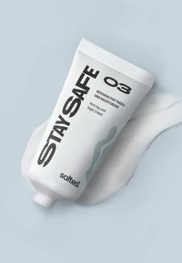 Tubo di plastica bianca con tappo a flip-top, caratterizzato da un testo nero in grassetto. L'etichetta indica "Crema Ricca Giorno e Notte" e il marchio "salted." Texture della crema chiara accanto.