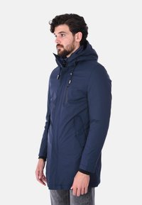 Giacca parka blu navy con cappuccio, zip frontale, due tasche laterali e dettagli con cordoncino. Realizzata in tessuto morbido e testurizzato.