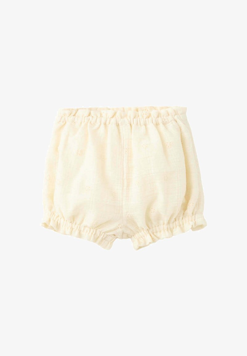 Bloomer pour bébé de couleur crème avec taille et ouvertures de jambes élastiques, présentant des détails floraux brodés subtils.