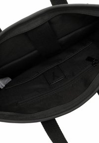 Czarna torba tote z materiału z zamykaną na zamek wewnętrzną kieszenią, strukturalnymi materiałami i mocnymi plecionymi uchwytami; minimalizm w designie, brak kontrastujących kolorów.