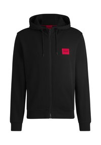 Sweat à capuche zippé noir en tissu doux, avec un patch logo rectangulaire rouge sur la poitrine gauche et une capuche avec cordon de serrage.