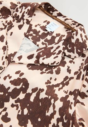 Brun og creme prikket bluse med en blød, silkeagtig tekstur, der har krave og et mærke indeni med teksten "NEXT time to dream."