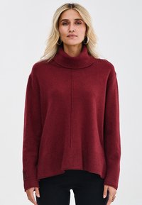 Burgundowa sweter dzianinowy z wysokim, prążkowanym kołnierzem, opadającymi ramionami i prążkowanym wykończeniem. Miękka tekstura z subtelnymi detalami szwów.