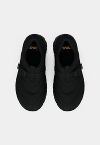 O pereche de pantofi negri slip-on pentru exterior, cu curea ajustabilă și talpă groasă, văzuți dintr-o poziție de sus pe un fond alb.