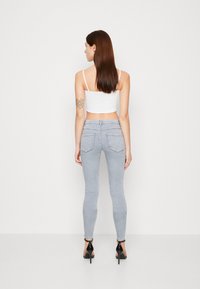 Jeans de tiro alto de color azul claro con un ajuste ceñido, que cuentan con bolsillos traseros y una textura suave. Combinados con una camiseta corta blanca.