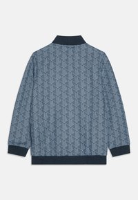 Chaqueta azul con estampado de diseño geométrico, cuello y puños de punto. Textura suave con un ajuste estructurado, adecuada para combinar en capas.