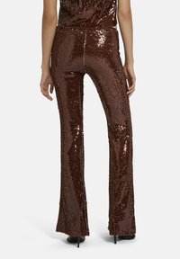 Bruine flonkerende flared broeken met een glanzend, gestructureerd oppervlak, voorzien van een hoge taille en een aansluitende pasvorm, die tot de enkels reikt.