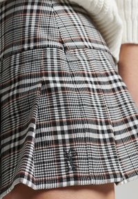Rutet mini skirt med sort, hvid og rød tern, fremstillet i et struktureret stof med plisseret design for ekstra detaljer.
