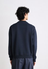 Felpa blu navy, tessuto morbido, collo a giro, maniche lunghe, polsini e orlo a costine, vestibilità rilassata, design minimalista senza loghi visibili.