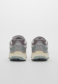 Gray sports shoes with a textured upper, mesh accents, cushioned sole, and subtle green highlights; features a rounded design and logo.